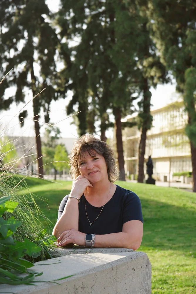 Christine L. Beltz smiling outdoors among the trees